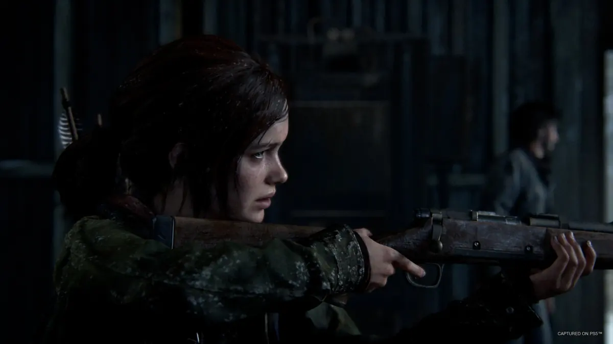 Screenshot von The Last of Us Part I, der Ellie mit einem Gewehr zeigt.